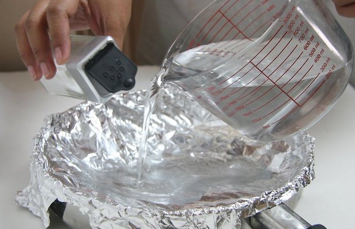 recipiente forrado de papel minio adicionando agua e detergente sobre
