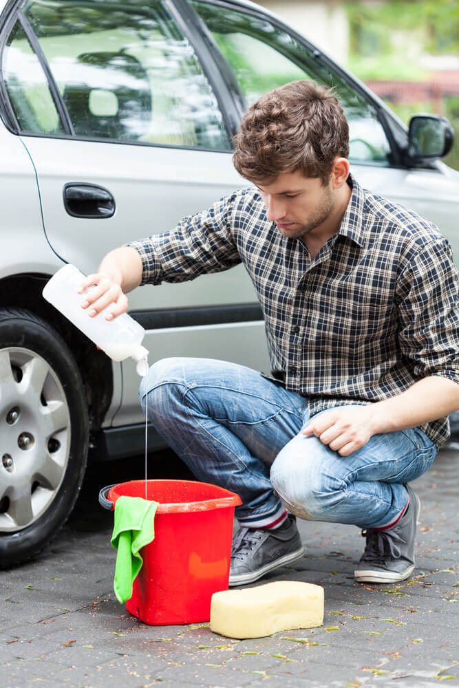 homem colocando sabao de carro num balde 