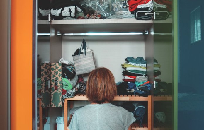 mulher olhando armário cheio e desarrumado